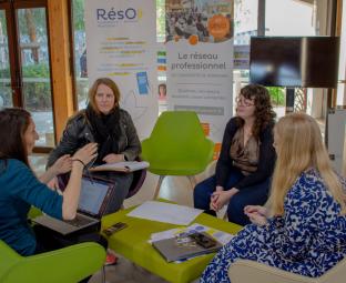 Quatre femmes blanches, assises dans des fauteuils verts et beiges, autour d'une petite table. Elles sont en train d'échanger. A l'arrière plan, un kakémo du Réseau professionnel de l'Université de Perpignan.