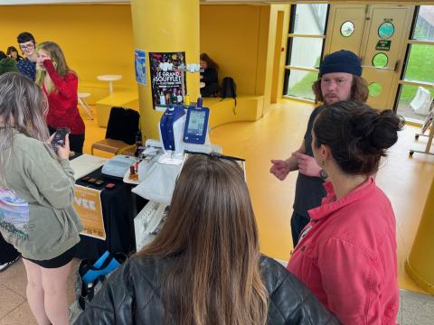 Photo de Thomas Mouchoux expliquant le fonctionnement de la brodeuse numérique à des étudiantes lors de la Campus Week