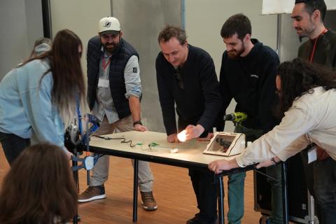 Photo de huit personnes réalisant une dynamo permettant de recharger un téléphone portable